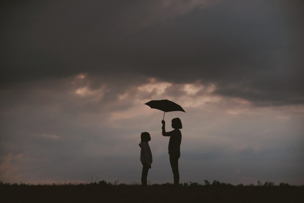 silhouette of adult holding umbrella over child to symbolize exploring needs & wants